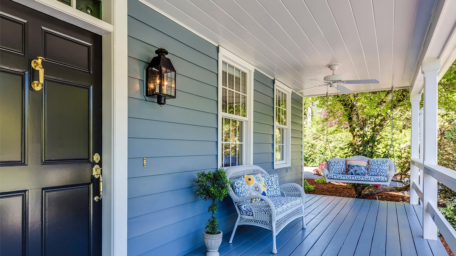 A porch with a wicker chair and a swing