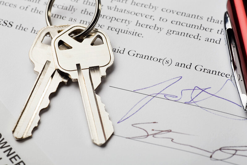A pair of keys sitting on top of a signed document